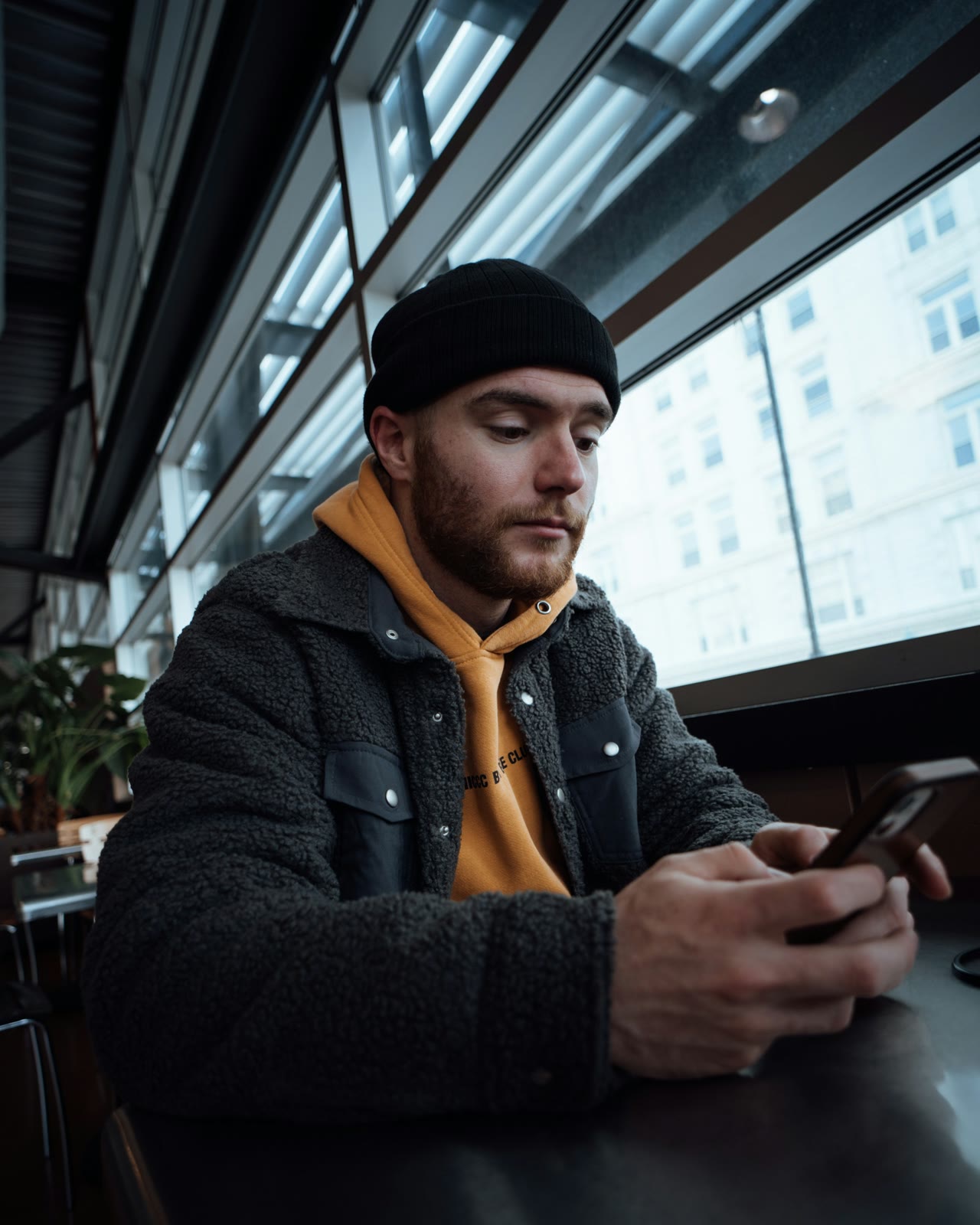 Mitarbeitergewinnung: Mann sitzt am Tisch und schaut auf sein Smartphone