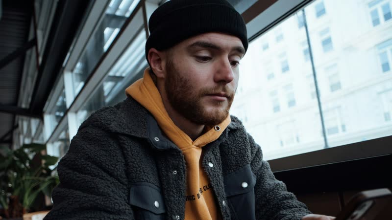 Mitarbeitergewinnung: Mann sitzt am Tisch und schaut auf sein Smartphone